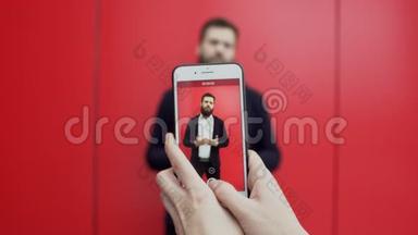 在电话里用红色背景拍摄了一段与会说话的黑发胡子男人的视频。 是谁的手